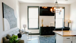 A modern living room with a sofa, a coffee table, a TV, and a dining area with a table and chairs.