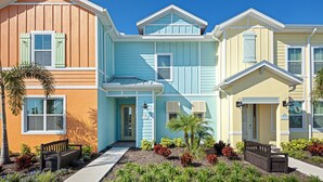 Une rangée de maisons aux couleurs vives, avec un jardin bien entretenu et un banc devant.