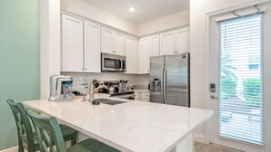 A modern kitchen with white cabinets, stainless steel appliances, and a marble countertop.