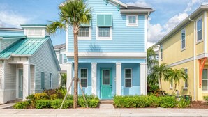 A two-story house with a blue exterior, white trim, and a green door.