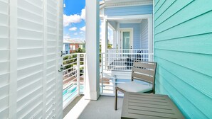A balcony with a white railing, a chair, and a view of a pool and neighboring buildings. - The Tipsy Turtle Cottage with Private Pool near Disney with Margaritaville. (Kissimmee)