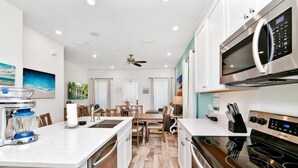 A modern kitchen with a central island, stainless steel appliances, and a dining area with a view of the outdoors.