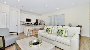 A modern living room with a sofa, coffee table, and a kitchen area in the background.