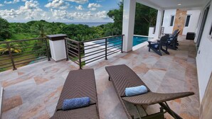 Un balcón con dos sillones de descanso y vista a la piscina.