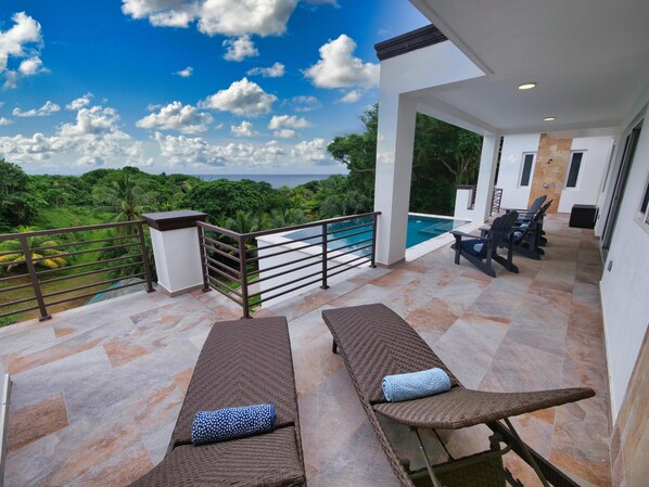 A balcony with two lounge chairs and a pool view.