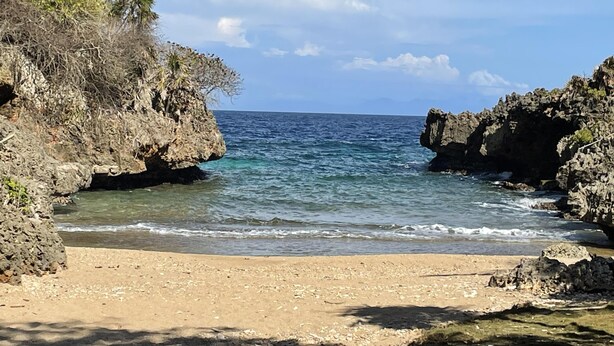 Una playa costera con acantilados rocosos y agua azul cristalina.