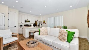 A modern living room with a sofa, coffee table, and a kitchen area in the background.