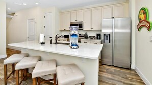 A modern kitchen with a central island, stainless steel appliances, and a water dispenser.