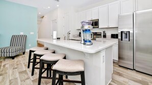 Una cucina moderna con isola centrale, elettrodomestici in acciaio inossidabile e una sedia a righe.