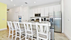 A modern kitchen with white cabinetry, stainless steel appliances, and a central island with bar stools. - Lime Green Villa near Disney | Margaritaville & Waterpark Access - 2972OR (Kissimmee)