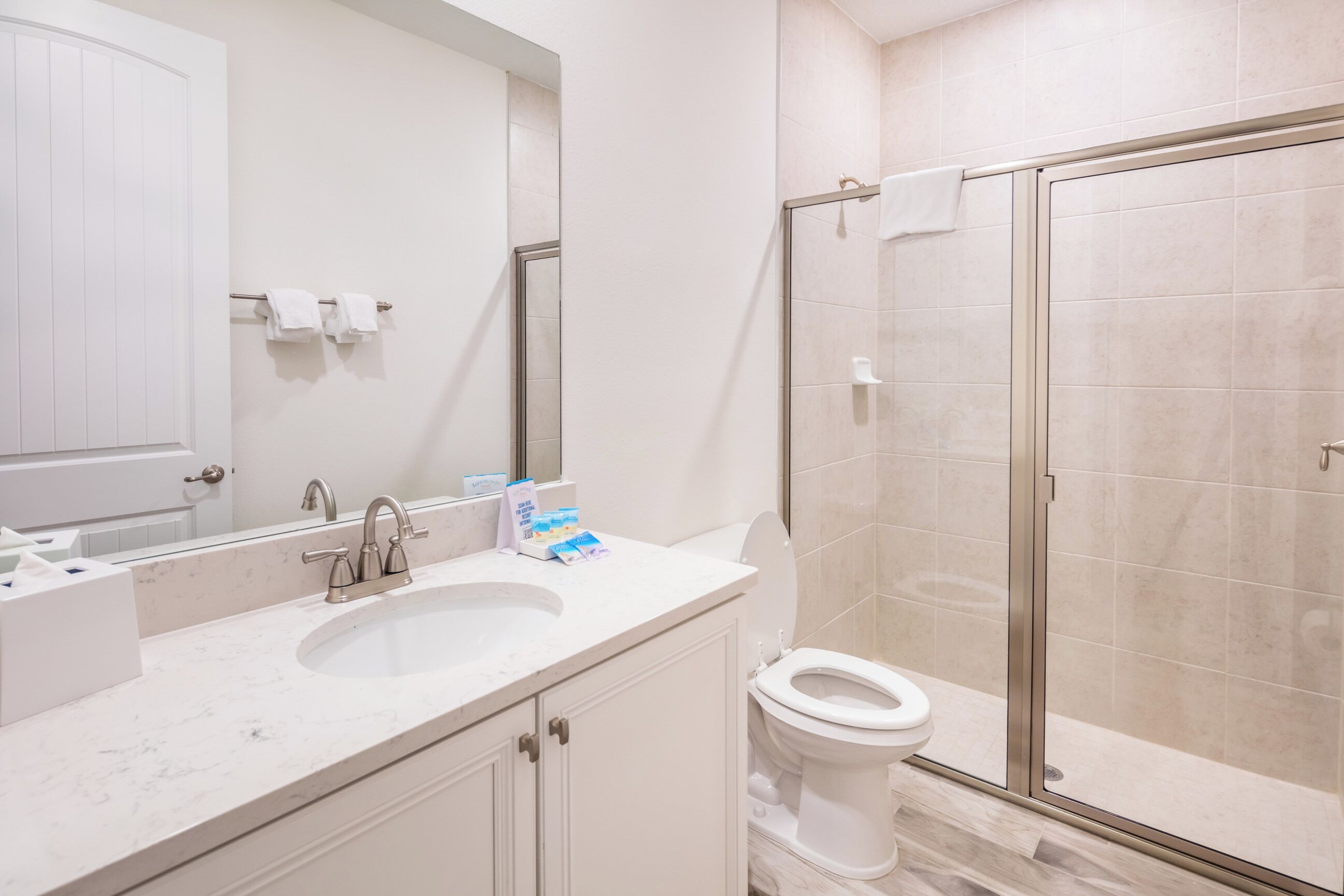 A modern bathroom with a sink, toilet, and glass shower enclosure.