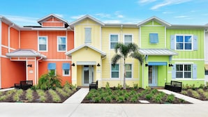 A row of colorful townhouses with a small garden in front.