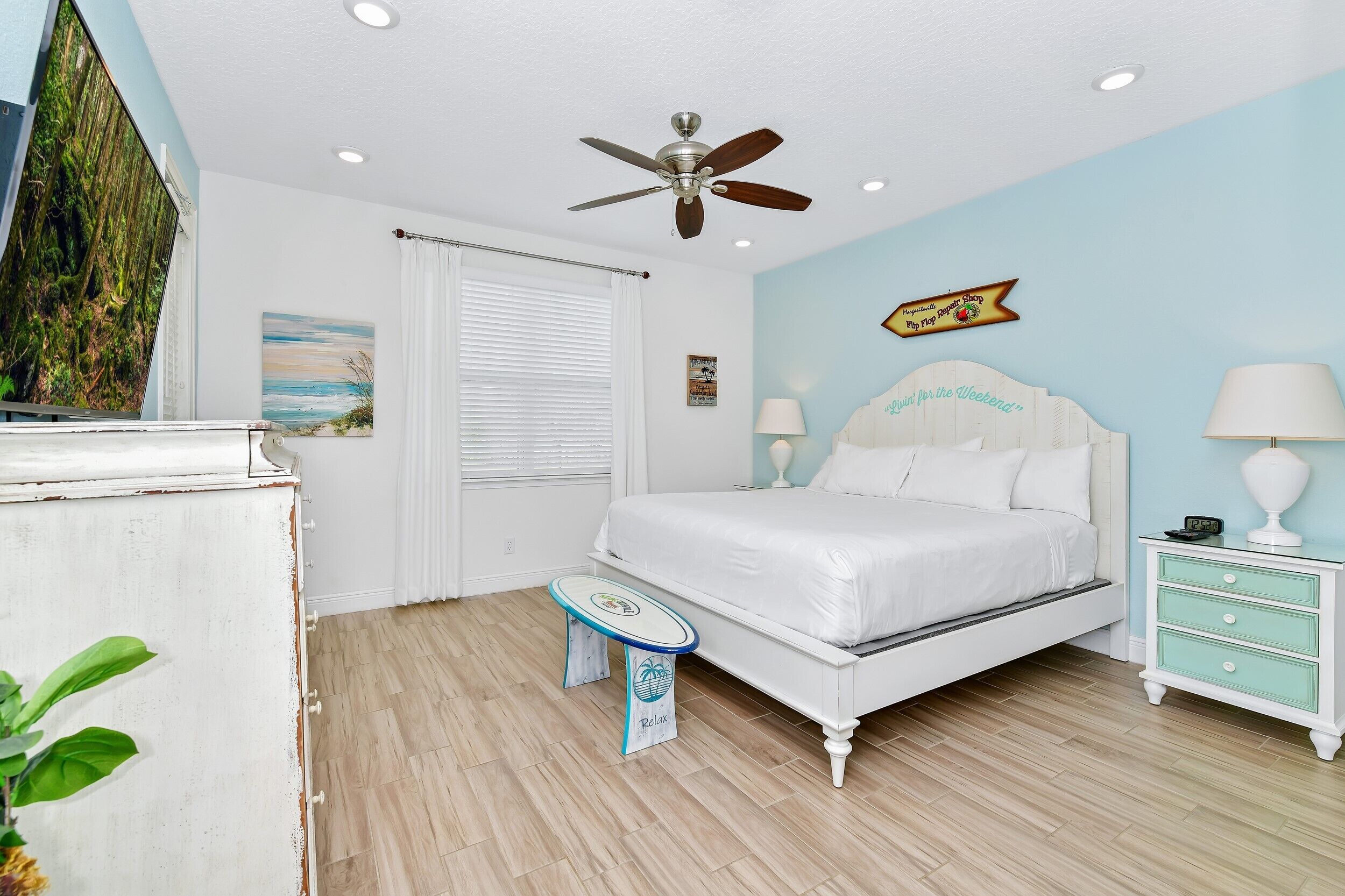 A bedroom with a bed, bedside tables, a ceiling fan, and a window with blinds.