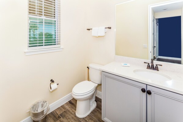 A bathroom with a toilet, sink, and mirror.