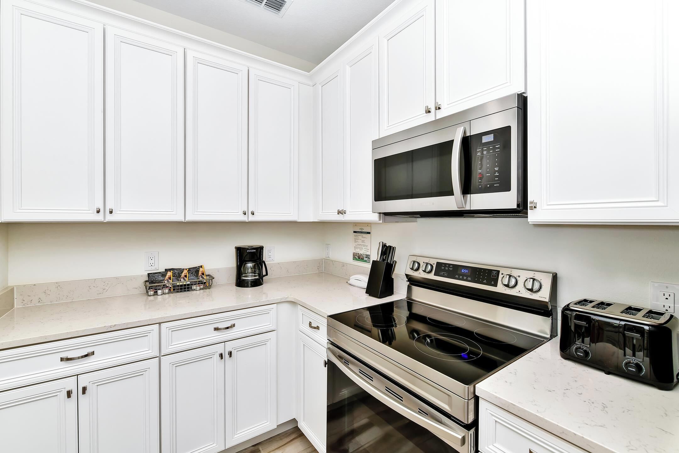 A kitchen with white cabinets, a microwave, an oven, and a toaster.