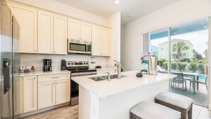 A modern kitchen with light-colored cabinets, stainless steel appliances, and a large island with bar stools.
