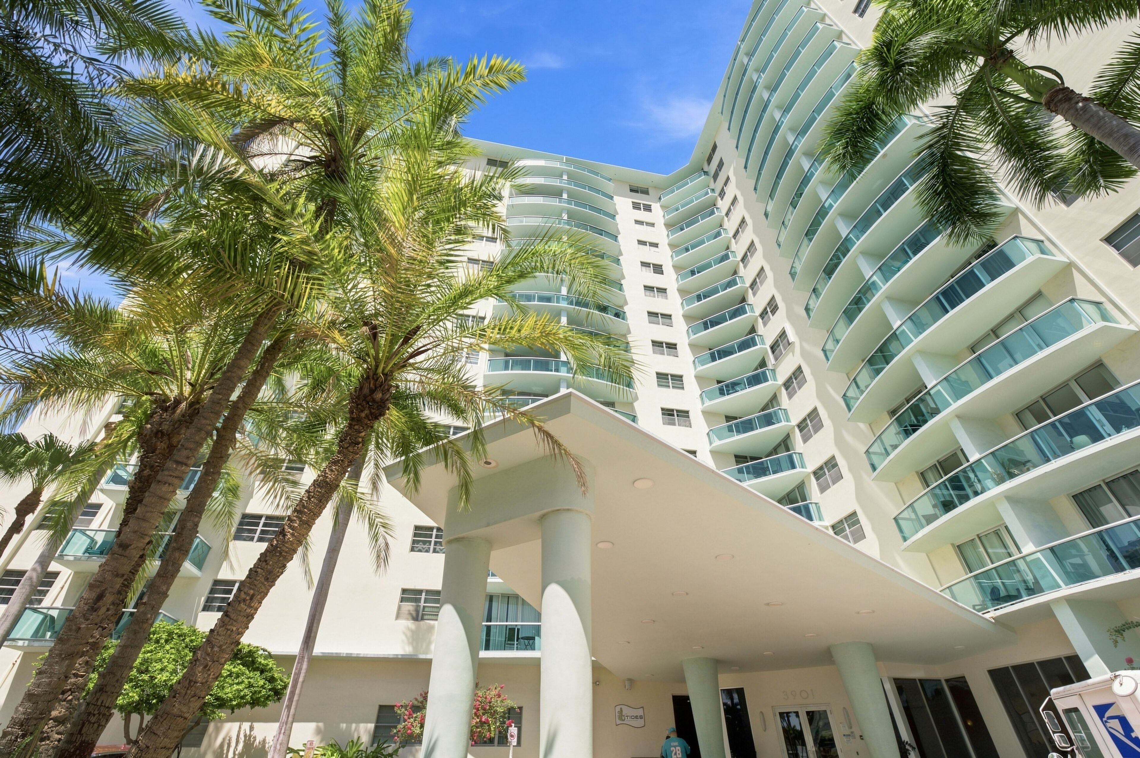 A multi-story hotel with a modern design, featuring balconies and a covered entrance area.