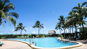 Une piscine avec des chaises longues et des palmiers.