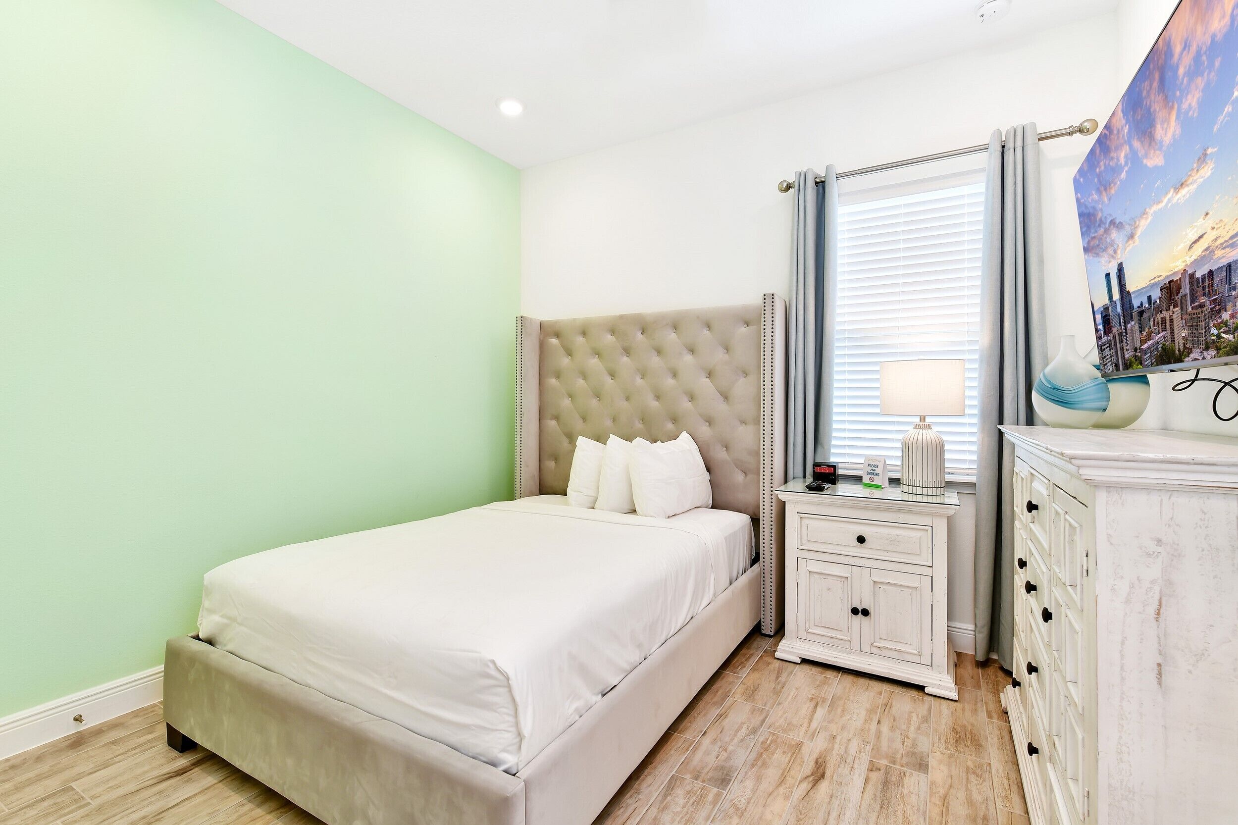 A neatly arranged bedroom with a bed, bedside table, and dresser.