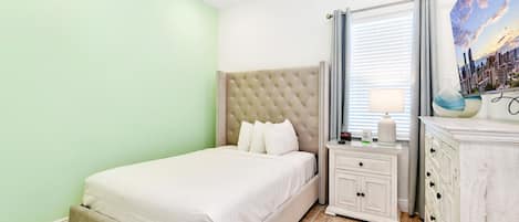 A neatly arranged bedroom with a bed, bedside table, and dresser.
