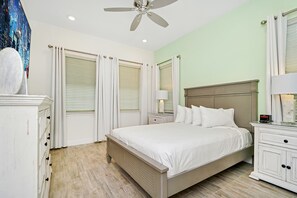 A bedroom with a bed, nightstands, a dresser, and a ceiling fan.