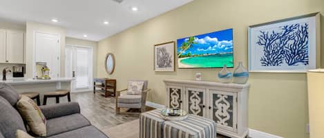 A living room with a sofa, a coffee table, a chair, a cabinet, and artwork on the wall.