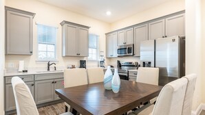 A modern kitchen with grey cabinets, a dark wooden dining table, and white chairs.