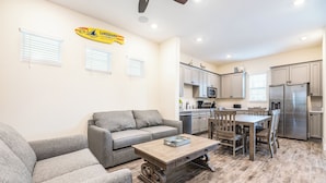 Un espacio habitable compacto con sofá, mesa de centro, mesa de comedor y cocina equipada con refrigerador y microondas.