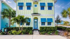 A two-story building with a light green facade, blue shutters, and a central entrance.