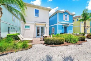 A two-story building with a patio area, outdoor seating, and a pool.
