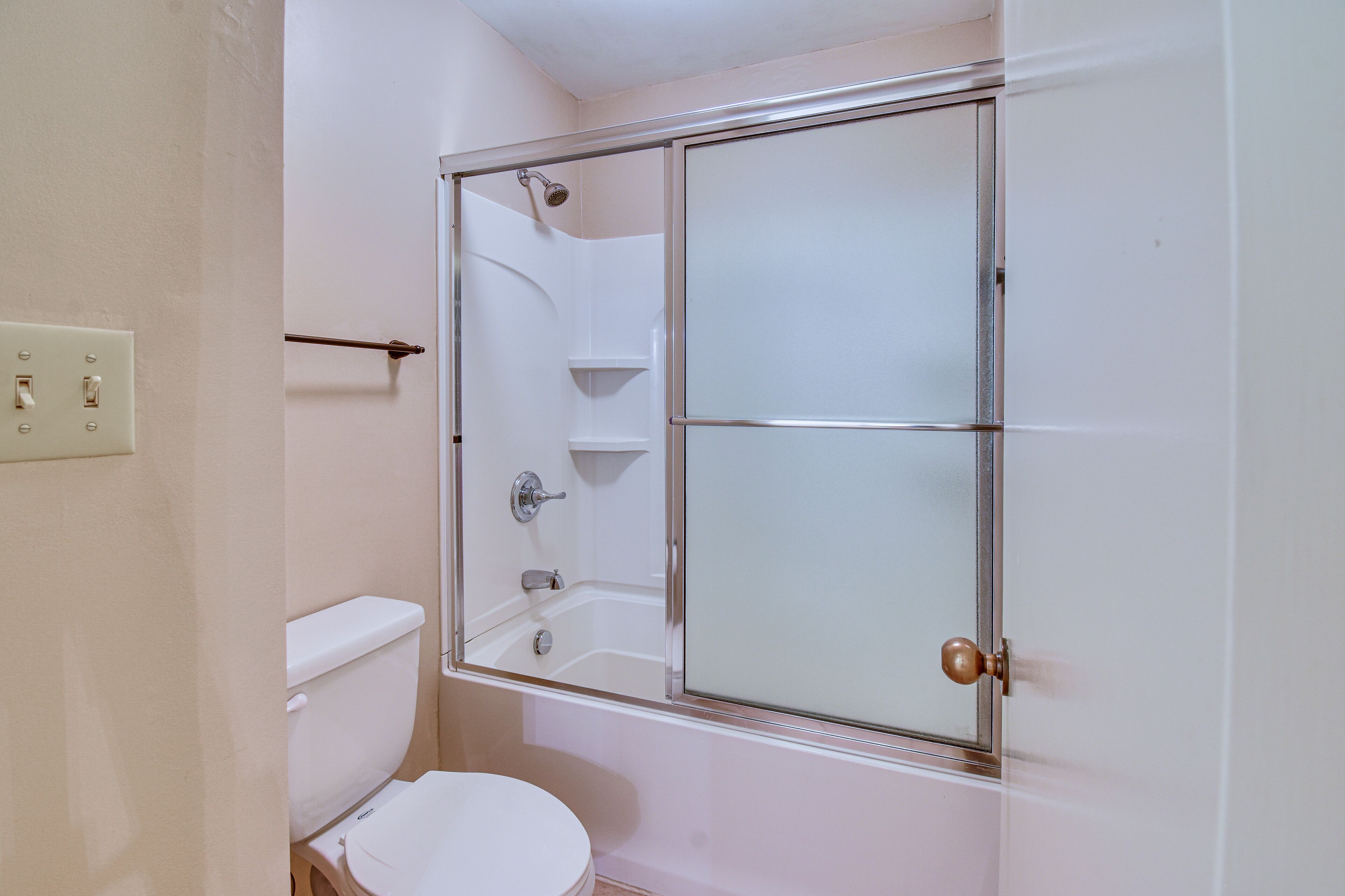 A bathroom with a glass-enclosed shower, a toilet, and a sink.
