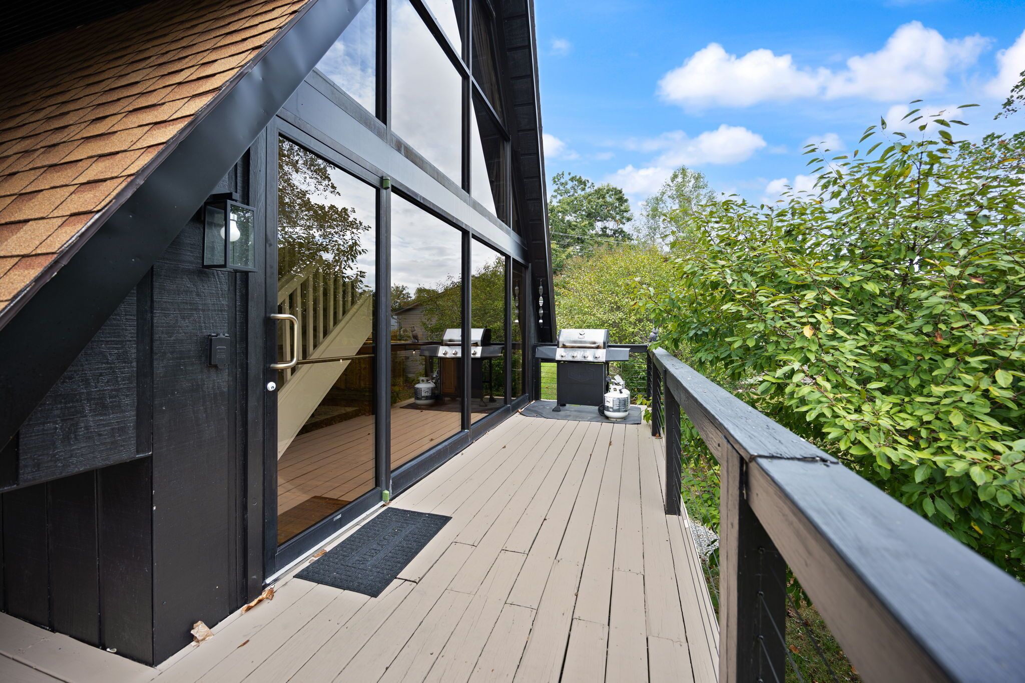 A modern house with a deck, large windows, and a barbecue area.