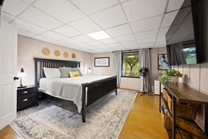 Un dormitorio con cama, mesita de noche, lámpara, decoración en la pared y una ventana con cortinas.