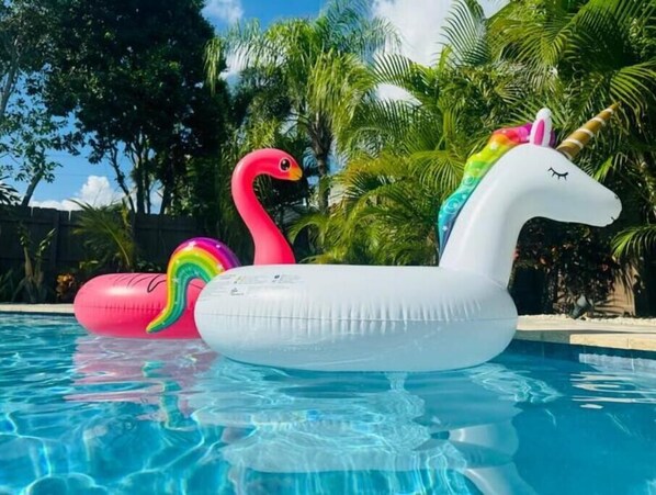 A pool with two inflatable floats, one shaped like a swan and the other like a unicorn.