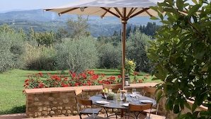 An outdoor dining area with a stone wall, a round table, and chairs.