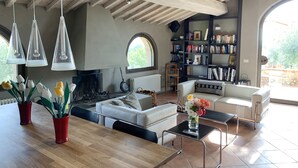 A modern living room with a fireplace, a bookshelf, and a dining area with tulips.