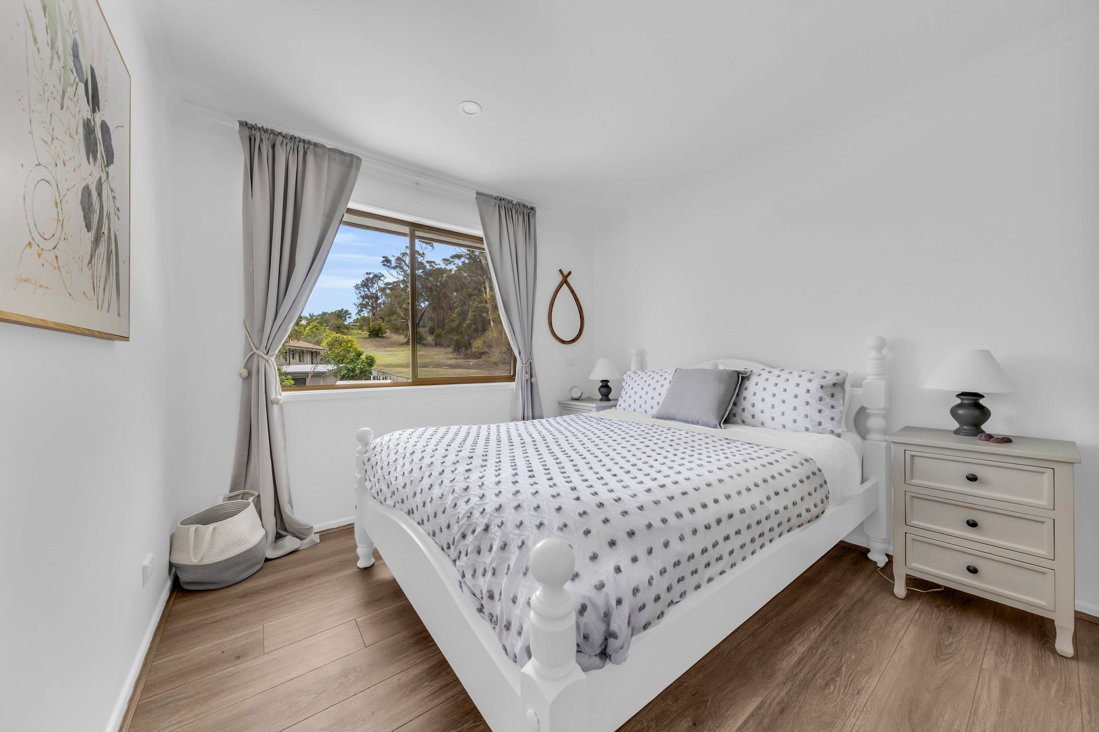Une chambre avec un grand lit, une table de chevet avec une lampe, une fenêtre avec des rideaux et une vue sur l’extérieur.