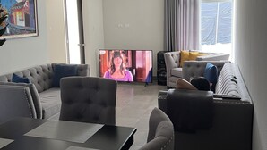 Una sala de estar con televisión, sofá y comedor.
