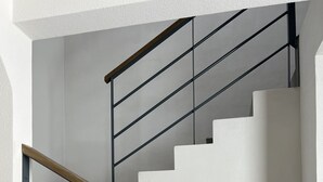 Una escalera moderna con barandilla de vidrio y pasamanos de madera, que da a una plataforma.