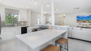 A modern kitchen with white cabinetry, a central island, and pendant lighting. - Vandy Villas — Walk to Vanderbilt Beach, Pool & Spa (Naples)