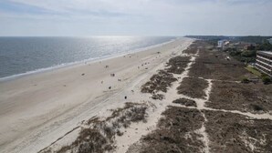 Une plage avec un rivage sablonneux et un sentier menant à un bâtiment.