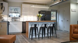 Una cocina moderna con armarios blancos, un refrigerador de acero inoxidable e una isla de madera con taburetes de bar.