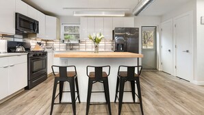 Una cocina moderna con una isla central, electrodomésticos de acero inoxidable y piso de madera.