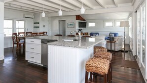 A spacious kitchen with a central island, wooden chairs, and a dining table. - Truro Beachfront House For a Group! (Provincetown)