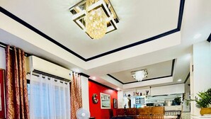 A modern living room with a dark blue sofa, a glass coffee table, and a red accent wall. - Cozy vacation home for family in Uptown Cagayan de Oro City Close to everything (Cagayan de oro city)