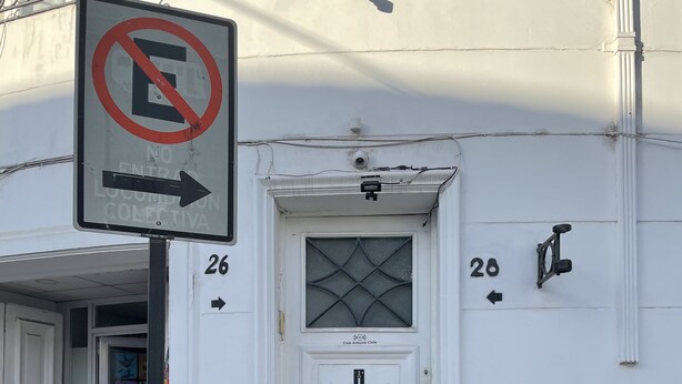 Un edificio blanco con un letrero de prohibido el acceso, una puerta con ventana y los números 26 y 28 en la pared.