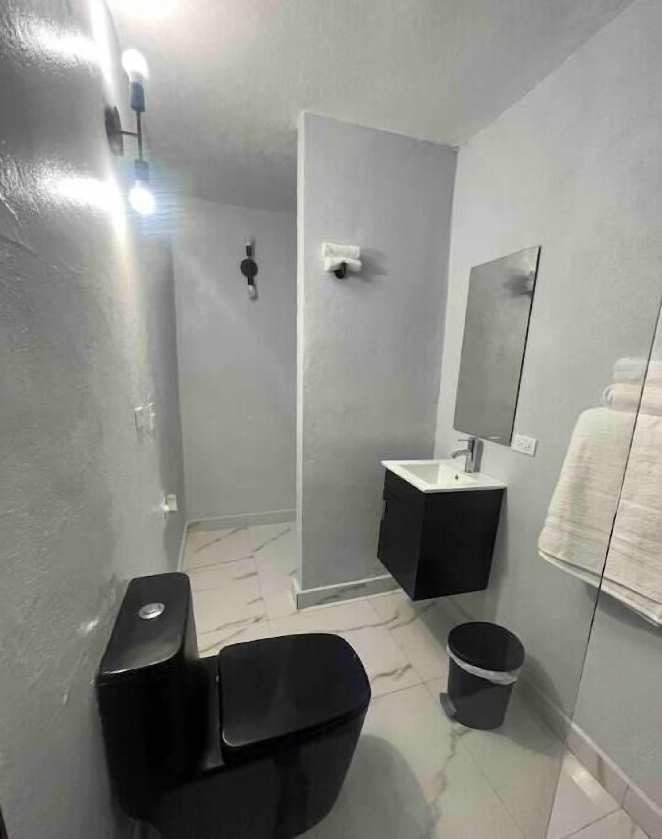 A compact bathroom with a toilet, sink, and mirror.