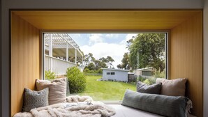 Un dormitorio con un ventanal grande, una cama con almohadas y vistas a un jardín trasero.