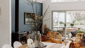 Una sala de estar moderna con chimenea, muebles de mimbre y un ventanal con vistas al exterior.