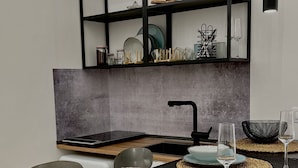 A modern kitchen with a black countertop, a built-in oven, and a black metal shelf above the sink.